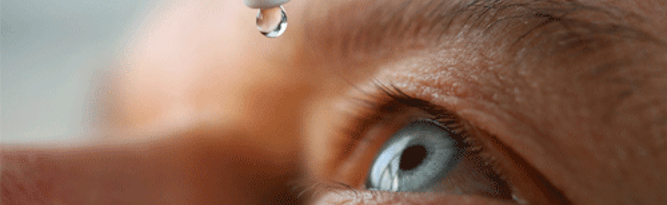 man putting drops in eye