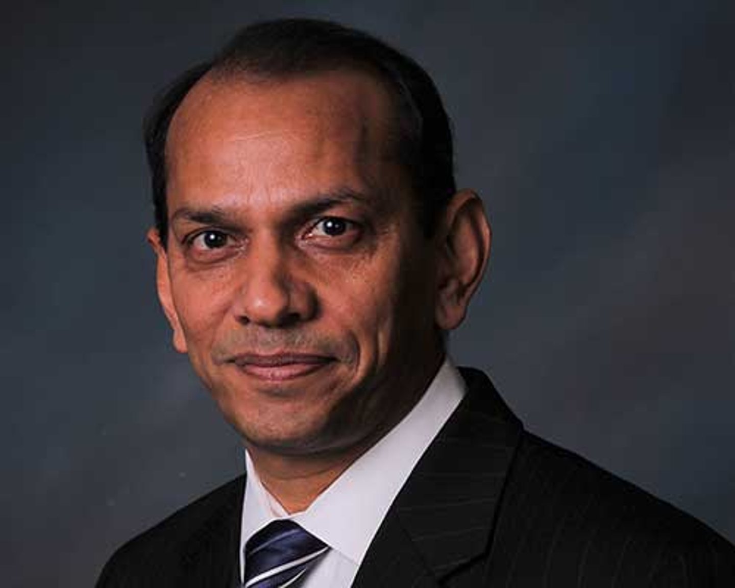 a man wearing a suit and tie smiling at the camera