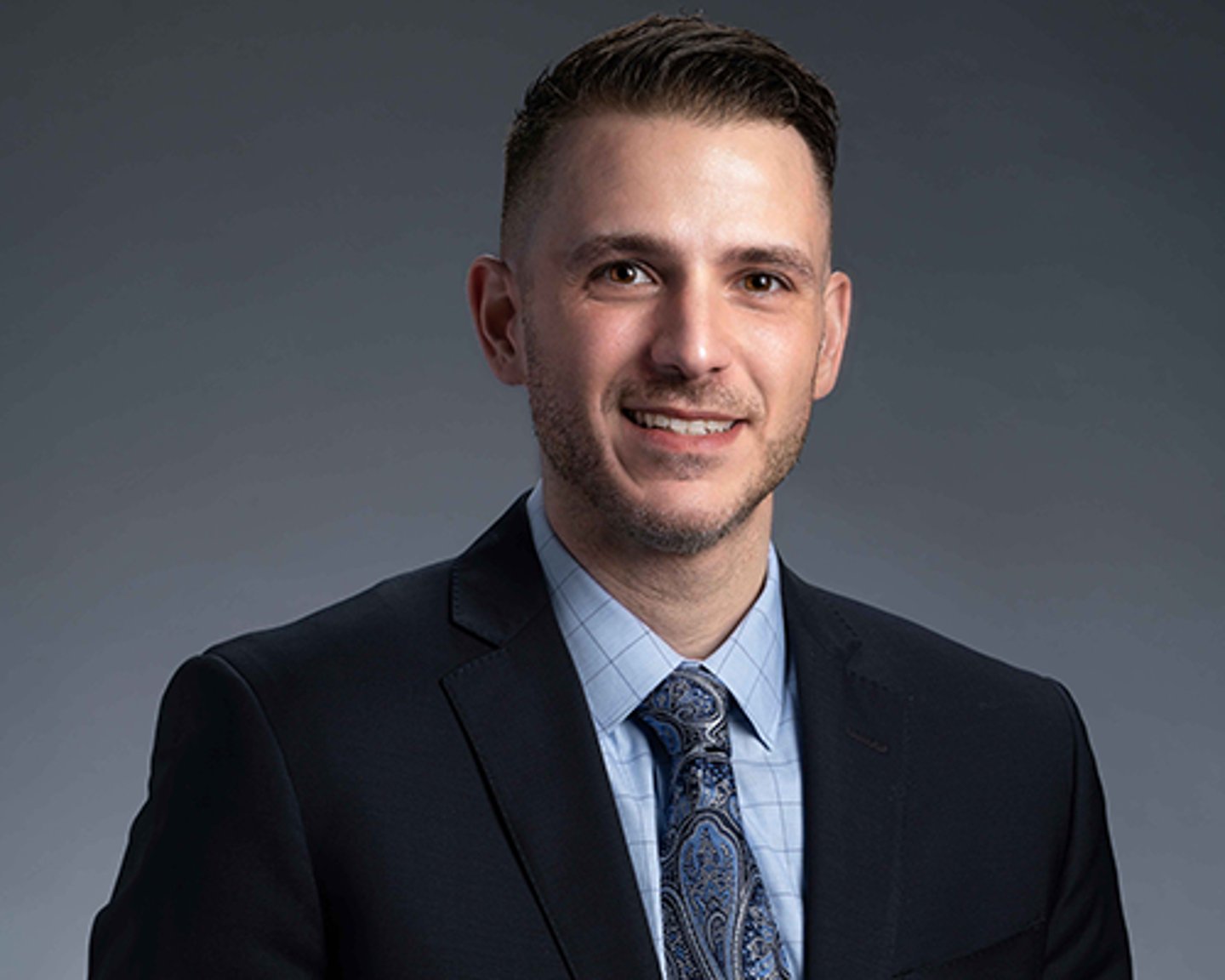 a man wearing a suit and tie smiling at the camera