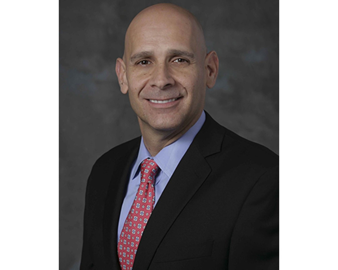 a man wearing a suit and tie smiling at the camera