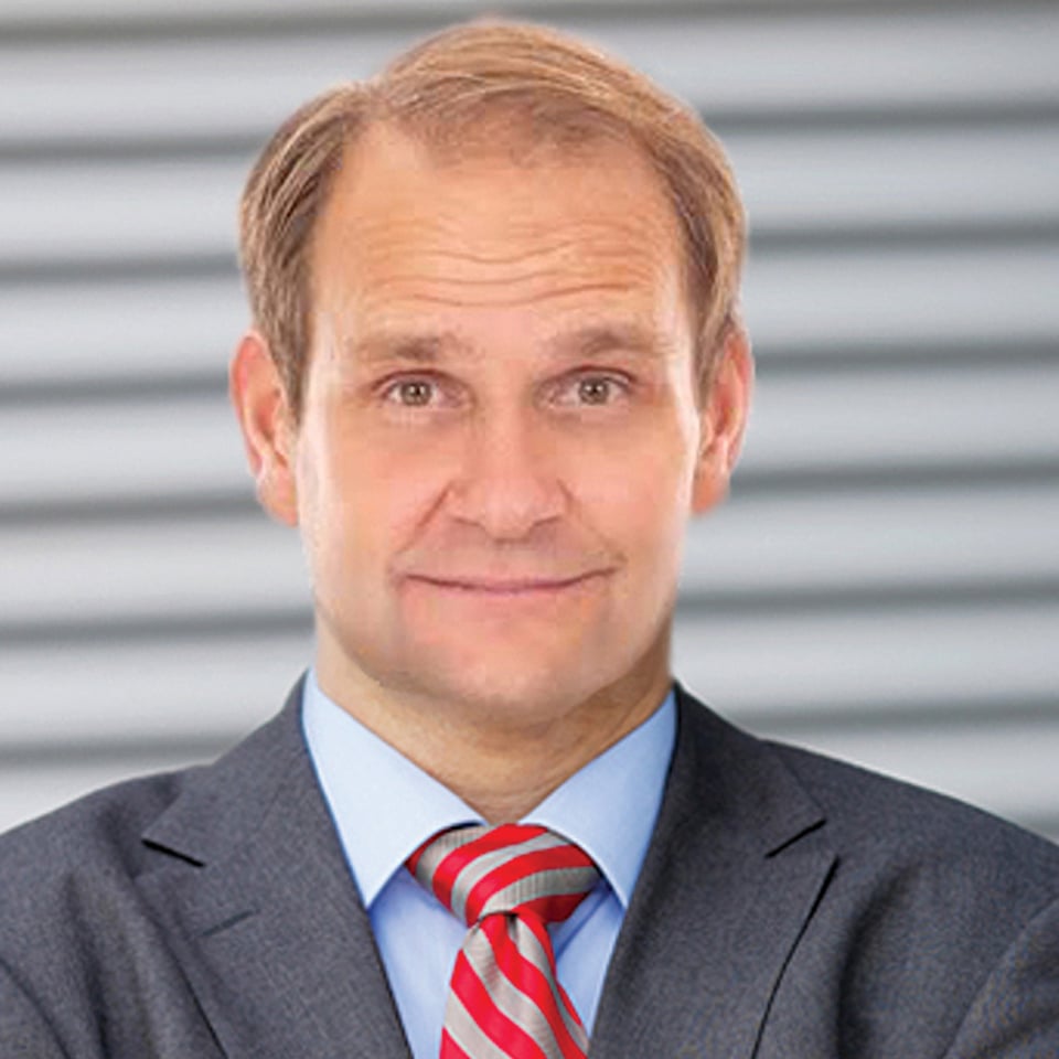 a man wearing a suit and tie smiling at the camera