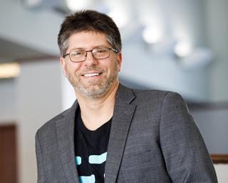 a man wearing glasses and smiling at the camera