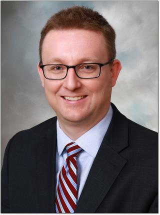 a man wearing a suit and tie smiling at the camera