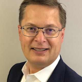 a man wearing glasses and smiling at the camera