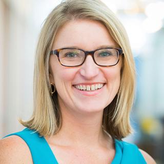 a woman wearing glasses and smiling at the camera