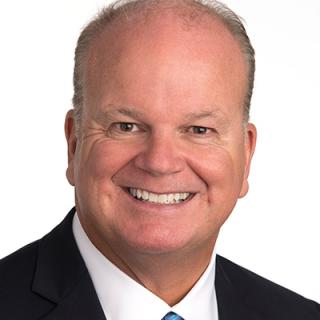 a man wearing a suit and tie smiling at the camera