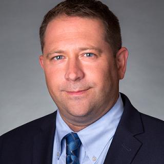 a man wearing a suit and tie smiling and looking at the camera