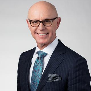 a man wearing a suit and tie smiling at the camera