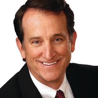 a man wearing a suit and tie smiling at the camera
