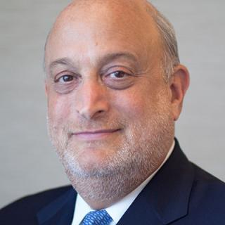 a man wearing a suit and tie smiling and looking at the camera