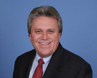 a man wearing a suit and tie smiling at the camera