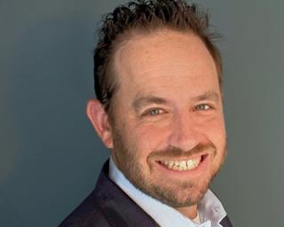 a man wearing a suit and tie smiling and looking at the camera