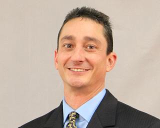 a man wearing a suit and tie smiling at the camera