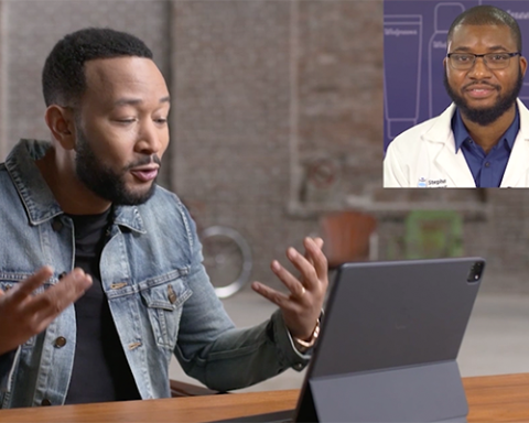 John Legend et al. sitting at a table using a laptop computer