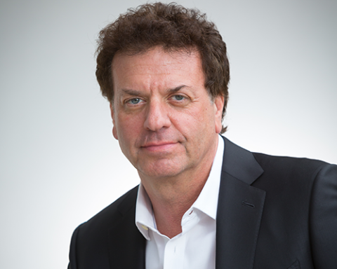a man wearing a suit and tie smiling and looking at the camera