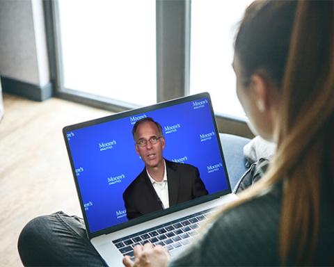 Mark Zandi sitting at a desk in front of a laptop computer