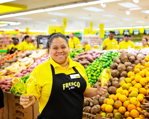 a person standing in front of a store filled with lots of fruit