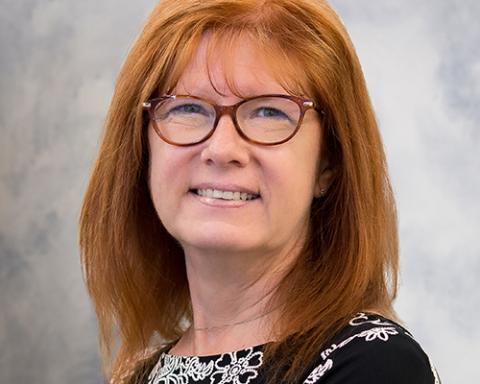 a close up of a person wearing glasses and smiling at the camera