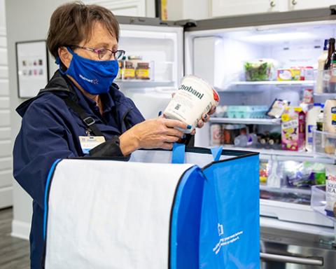a person in a blue shirt standing in front of a refrigerator