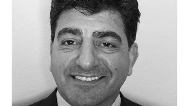 a man wearing a suit and tie smiling at the camera